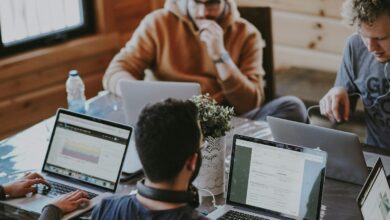 Pessoas trabalhando juntas com notebooks em uma mesa