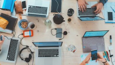 Mesa compartilhada com computadores e materiais de trabalho